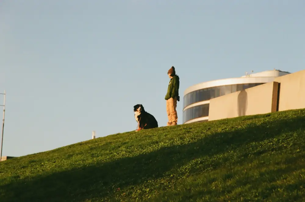 Two people on a grassy hill near a building